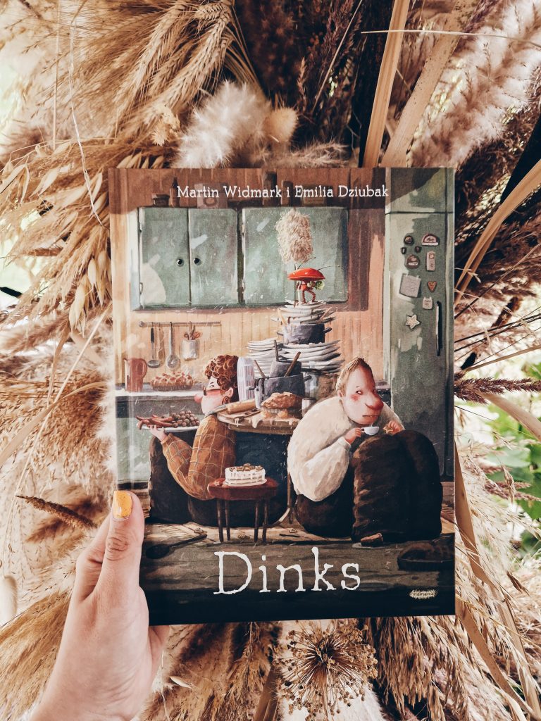 na zdjęciu znajduje się ręka trzymająca książkę dinks Martina Widmarka i Emilii Dziubak